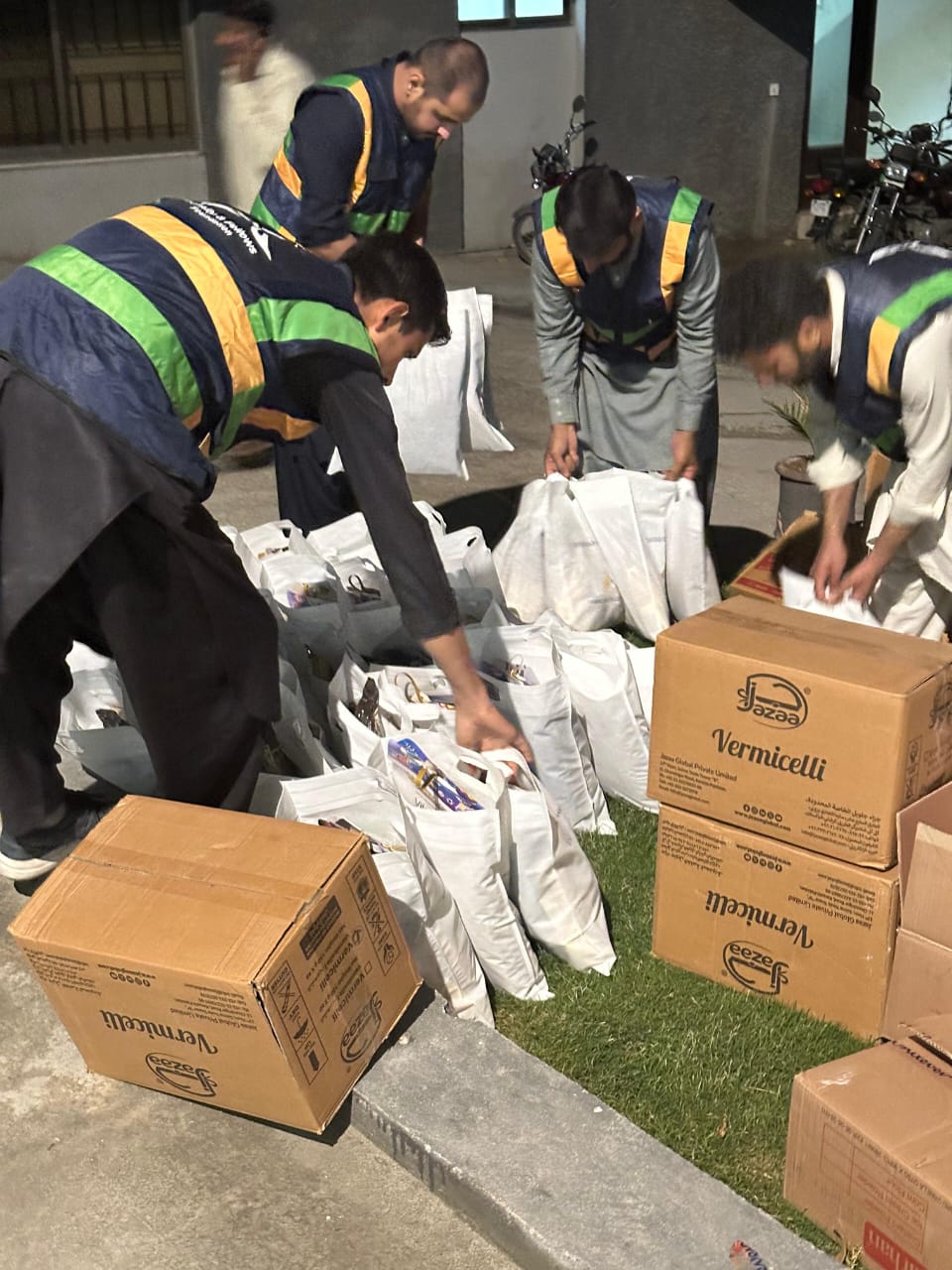 Volunteers packing Eid assistance bags at night